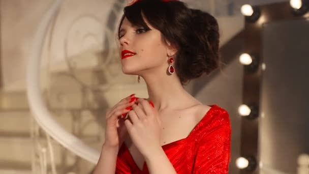 Detailní mladé dívky nádherné módní retro klobouk a červených šatech, Bruneta model s červenými rty make-up, elegantní účes, přívěsek ženy sada šperky představují zrcadlo s žárovkami pro make-up v oblékání