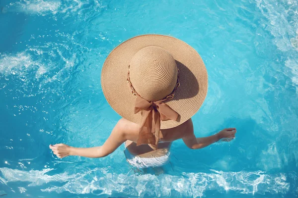 后视图的女人在游泳池里放松的草帽上周转率 — 图库照片