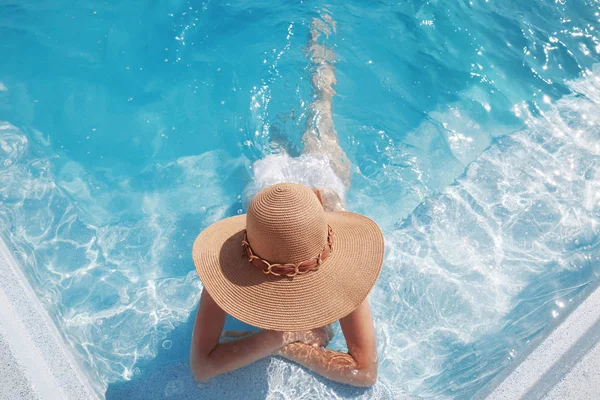 Vue du dessus de la femme en chapeau de paille relaxant dans la piscine à luxu — Photo