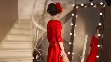 Retro şapka ve kırmızı elbise genç kız güzel moda portre, esmer modeli ile kırmızı dudaklar makyaj, zarif saç modeli, kolye kadınlar tarafından ayna soyunma makyaj için ampuller ile poz Takı Seti
