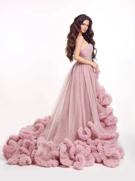 a brunette with long hair in a red dress poses in the studio on the stairs  Stock Photo by Lobachad