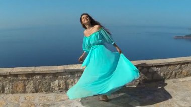 Sağlıklı uzun saçlı kız elbise üfleme gülümseyen güzel esmer. Mutlu genç kadın zevk doğa ve deniz ve mavi gökyüzü Eğleniyor. Sveti Stefan, Karadağ.