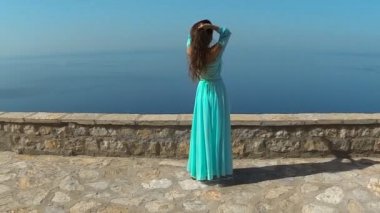 Sağlıklı uzun saçlı kız elbise üfleme gülümseyen güzel esmer. Mutlu genç kadın zevk doğa ve deniz ve mavi gökyüzü Eğleniyor. Sveti Stefan, Karadağ.