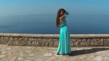 Sağlıklı uzun saçlı kız elbise üfleme gülümseyen güzel esmer. Mutlu genç kadın zevk doğa ve deniz ve mavi gökyüzü Eğleniyor. Sveti Stefan, Karadağ.