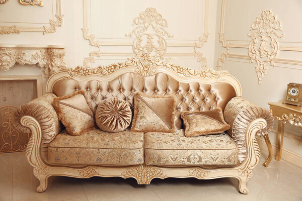 Royal sofa with pillows in beige luxurious interior with ornamen