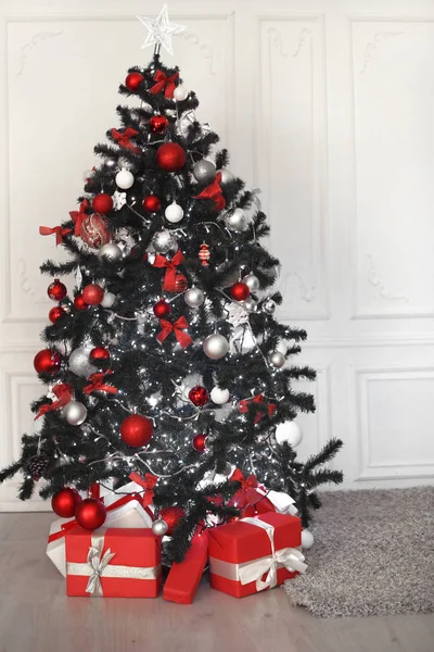 Рождественская елка с красными подарками украшения перед белой стеной в хо — стоковое фото
