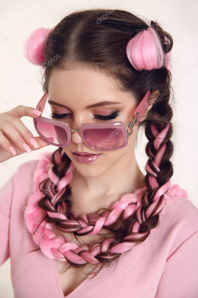 Brunette teen girl braided with two french braids from pink kanekalon in a beauty salon. Professional hair care and creating hairstyles. Fashion summer sunglasses.