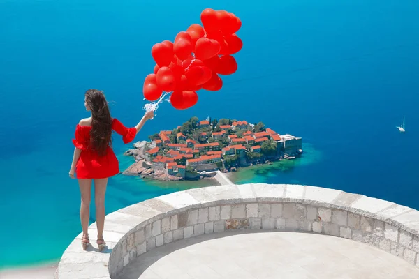 Romantic girl with heart balloons over Sveti Stefan island in Bu — Stock Photo, Image