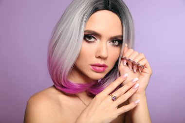Güzel bayan ametist yüzük ve bilezik takısı seti sunar. Ombre Bob kısa saç stili ve manikürlü tırnaklı kadın portresi. Güzellik makyajı. Mor arkaplanda izole edilmiş muhteşem bir model.