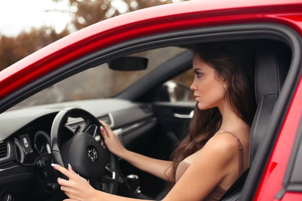 赤い車を運転しながら道路を探してドレスで魅力的な若い女性のプロファイルのクローズアップ肖像画 自信と美しさ 自動車のコンセプト — ストック写真