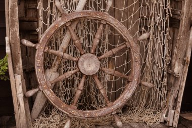 Ağlı ahşap tekne duvarı kompozisyonu ve balıkçı ağı ve tekerlek miğferi. Sanat desing. 