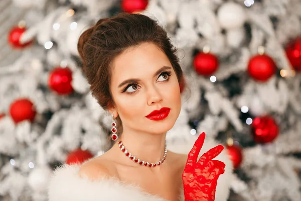 穿着红宝石珠宝和红色手套的优雅女人的冬季肖像 美丽的黑发女士 有着婚纱的发型 漂亮的妆容覆盖着圣诞树的背景 — 图库照片