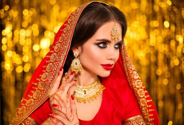 Altın bokeh üzerinde kırmızı sarili güzel Hintli kız portresi. Kundan mücevherli genç Hindu kadın model. Geleneksel Hint kostümü lehenga choli. Kına resmi, gelinin ellerinde mehendi..