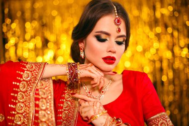 Altın bokeh üzerinde kırmızı sarili güzel Hintli kız portresi. Kundan mücevherli genç Hindu kadın model. Geleneksel Hint kostümü lehenga choli. Kına resmi, gelinin ellerinde mehendi..
