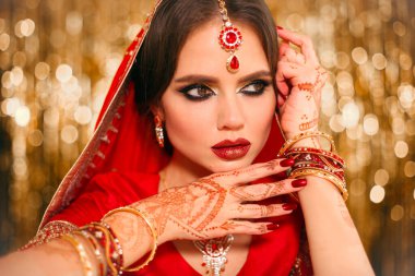Altın bokeh üzerinde kırmızı sarili güzel Hintli kız portresi. Kundan mücevherli genç Hindu kadın model. Geleneksel Hint kostümü lehenga choli. Kına resmi, gelinin ellerinde mehendi..