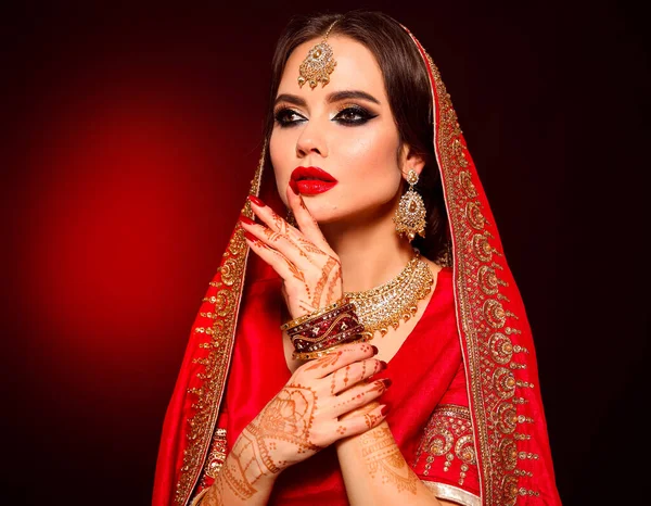 Kızıl gelinlik giymiş güzel Hintli bir kızın portresi. Kundan mücevher seti olan genç Hindu kadın model. Geleneksel Hint kostümü lehenga choli. Kına resmi, gelinin ellerinde mehendi..