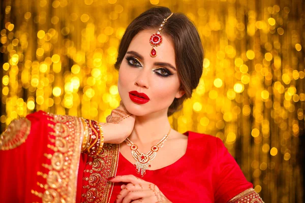 黄金のボケに赤いブライダルサリで美しいインドの女の子の肖像画 Kundanジュエリーと若いHindu女性モデル 伝統的なインドの衣装Lehenga Choli ヘンナ ペインティング花嫁の手にメヘンディ — ストック写真