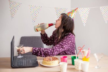 Genç bir kadın doğum gününü internette alkol içerek kutluyor. Video konferans dizüstü bilgisayarı parti interneti. Alkolizm yeni teknoloji karantinası sosyal izolasyon. Boş zaman. Görüntülü konuşma arkadaşlar tebrikler.