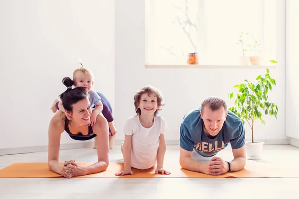 Tam bir genç aile evde spor yapıyor. Anne baba bebek yoga egzersizleri yapıyor. Sevgi kardeşleri çok güzel. Kendini karantinaya alma eğitimi. Sağlıklı bir yaşam tarzı. Aktivite sağlık sabahı çocuğu