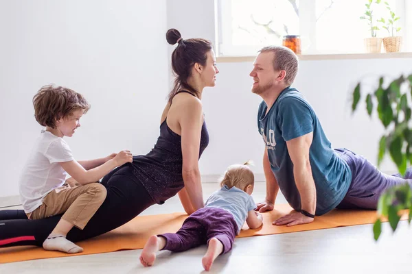 Tam bir genç aile evde spor yapıyor. Anne baba bebek yoga egzersizleri yapıyor. Aşk armonisi cennet gibi. Kendini karantinaya alma eğitimi. Sağlıklı bir yaşam tarzı. Aktivite sağlık sabahı çocuğu