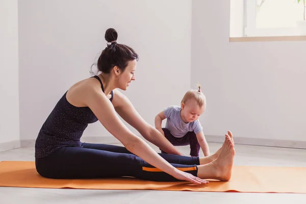 Mother goes in for sports with her daughter play at home. Gymnastics for kids. Little gymnast stretching. Healthy lifestyle leisure workout in the apartment. Courses mom and baby gym. Modern family