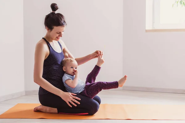 Mother goes in for sports with her daughter play at home. Gymnastics for kids. Little gymnast stretching. Healthy lifestyle leisure workout in the apartment. Courses mom and baby gym. Modern family