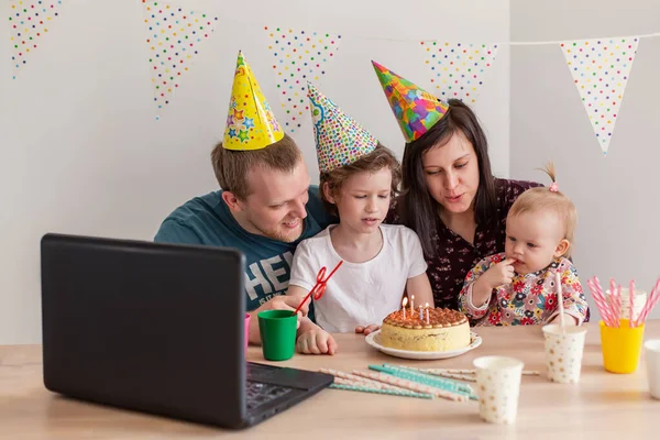 Büyük bir aile online doğum gününü kutluyor. Anne baba videodaki çocuklar kendilerini izole ediyorlar. Dizüstü bilgisayarda parti yeni teknoloji aletleri. Coronavirus karantinaya alındı. Mutluluk pastası. Tebrikler.