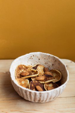 Küçük krep gevrekleri karantinaya alındı. Kahvaltıda evde fındık ve tereyağlı tatlı var. Ahşap bir masa arkasında ev yapımı ızgara yemek. Metin için Mini Üst Görünüm 