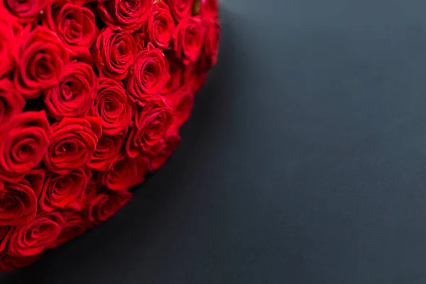 Kırmızı güller siyah arka plan pankartı. Bir buket çiçek. Çiçekçi dükkanından kartpostal. Metin kopyalama alanı için boşluk. Yıldönümü kutlaması. 14 Şubat Sevgililer Günü. 8 Mart Anneler Günü koyu renk kontrast