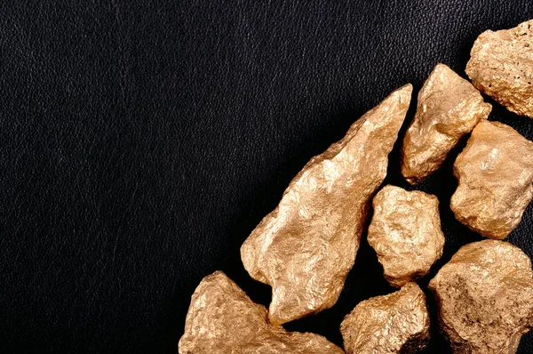Bryłki złota na skórzane czarne tło. Zbliżenie. — Zdjęcie stockowe