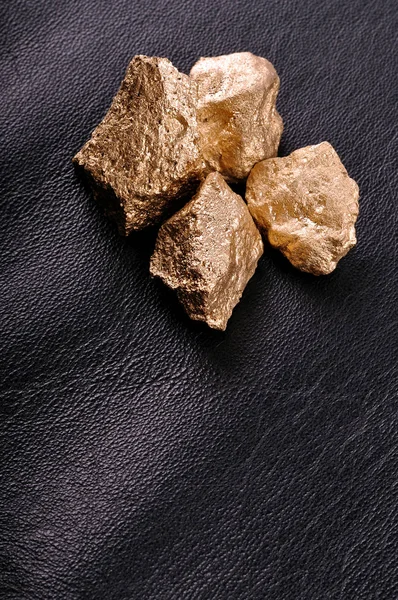 Pepite d'oro su uno sfondo di pelle nera. Primo piano . — Foto Stock