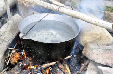 Açık ateş yerinde eski turist tenceresi ile yemek pişirme. Yaz 