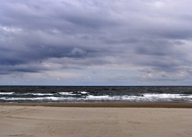 Panorama, fırtına gelmeden önce akşam alacakaranlık kıyısında ağır dalga ve rüzgardır ve alanın sığ odak derinliğiyle görüntü alıyor