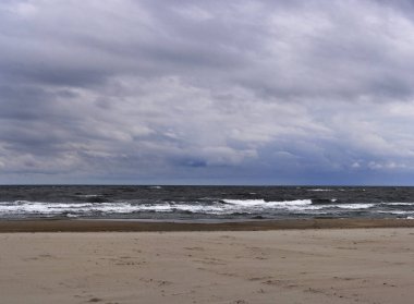 Panorama, fırtına gelmeden önce akşam alacakaranlık kıyısında ağır dalga ve rüzgardır ve alanın sığ odak derinliğiyle görüntü alıyor
