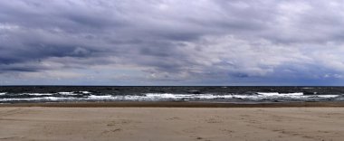 Panorama, fırtına gelmeden önce akşam alacakaranlık kıyısında ağır dalga ve rüzgardır ve alanın sığ odak derinliğiyle görüntü alıyor