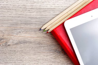 Kırmızı günlük defter, beyaz tablet ve renkli kalemler masa üzerine woo