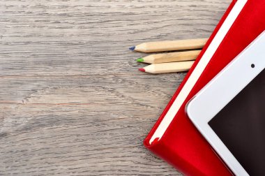 Kırmızı günlük defter, beyaz tablet ve renkli kalemler masa üzerine woo