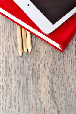 Kırmızı günlük defter, beyaz tablet ve renkli kalemler masa üzerine woo