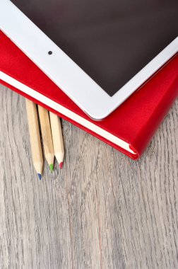 Kırmızı günlük defter, beyaz tablet ve renkli kalemler masa üzerine woo