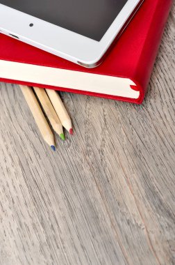 Kırmızı günlük defter, beyaz tablet ve renkli kalemler masa üzerine woo