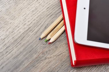 Kırmızı günlük defter, beyaz tablet ve renkli kalemler masa üzerine woo