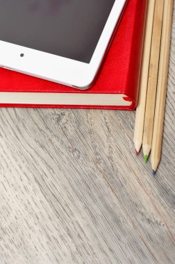 Kırmızı günlük defter, beyaz tablet ve renkli kalemler masa üzerine woo