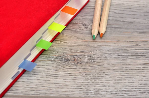 赤い日記帳ノートとデスク木目テクスチャに色鉛筆. — ストック写真