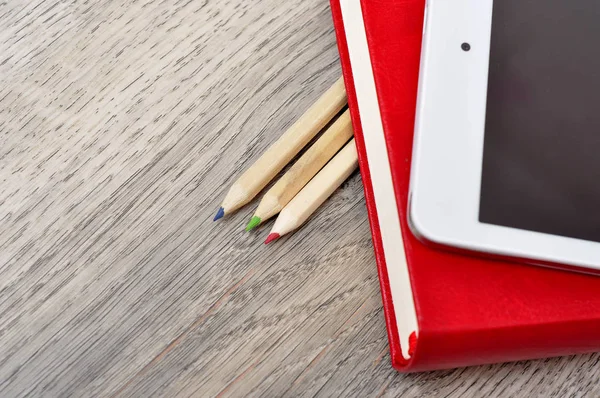 Kırmızı günlük defter, beyaz tablet ve renkli kalemler masa üzerine woo