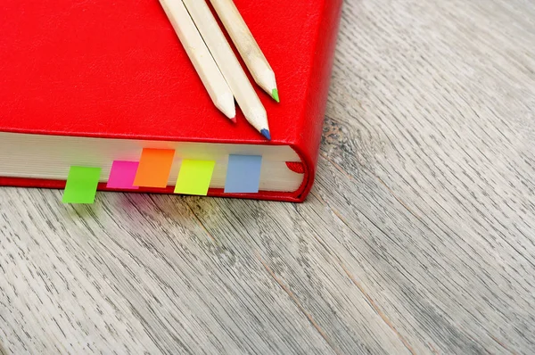 Pamiętnik czerwony Notes i kredki na tekstury drewniane biurko. — Zdjęcie stockowe
