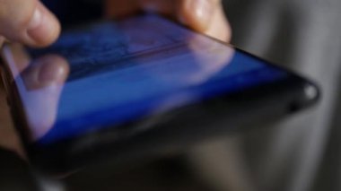 Bir akıllı telefonun dokunmatik ekranındaki sosyal medya paylaşımlarını karıştıran birinin sığ DOF görüntüsüyle son derece yakın çekim.