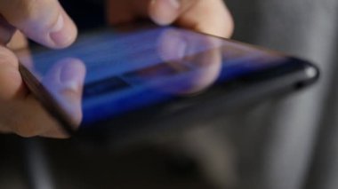 Bir akıllı telefonun dokunmatik ekranındaki sosyal medya paylaşımlarını karıştıran birinin sığ DOF görüntüsüyle son derece yakın çekim.