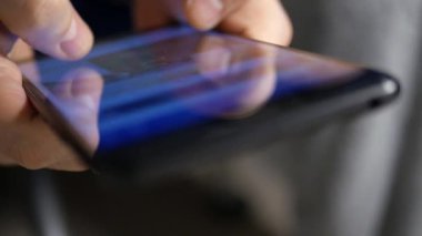 Bir akıllı telefonun dokunmatik ekranındaki sosyal medya paylaşımlarını karıştıran birinin sığ DOF görüntüsüyle son derece yakın çekim.