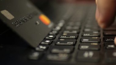 Laptop klavyesinde siyah platin kredi kartıyla ödeme, süper clouse-up, makro. 