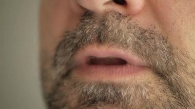 Gri sakallı bir adam virüsten bir hap yutuyor, koronavirüs oluyor ve alaycı bir yüz ifadesi takınıyor. Süper makro yakın çekim.